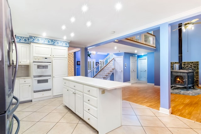 kitchen featuring white cabinets, a center island, light hardwood / wood-style floors, and a wood stove