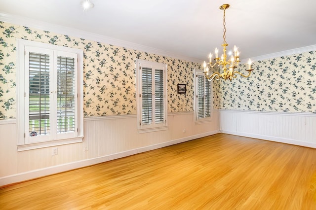 unfurnished room with hardwood / wood-style flooring, a notable chandelier, and ornamental molding