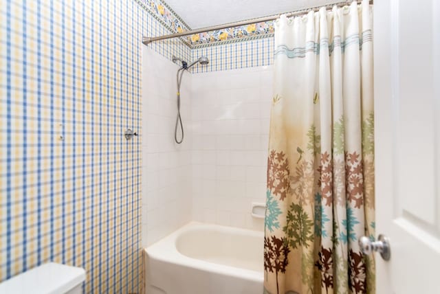 bathroom featuring shower / bathtub combination with curtain, a textured ceiling, and toilet