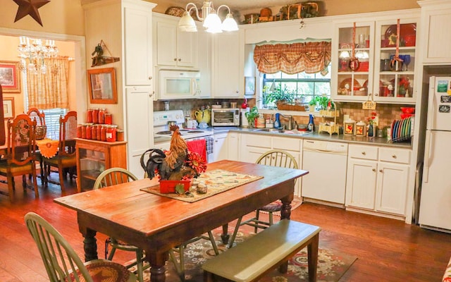 kitchen featuring hanging light fixtures, backsplash, white appliances, a notable chandelier, and sink