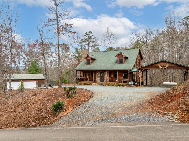 view of front facade featuring log siding, a carport, a chimney, gravel driveway, and a porch