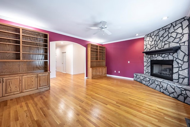 unfurnished living room featuring ceiling fan, crown molding, light hardwood / wood-style floors, and a fireplace