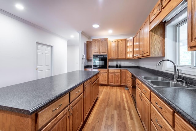 kitchen featuring sink, black appliances, ornamental molding, light hardwood / wood-style flooring, and a kitchen island