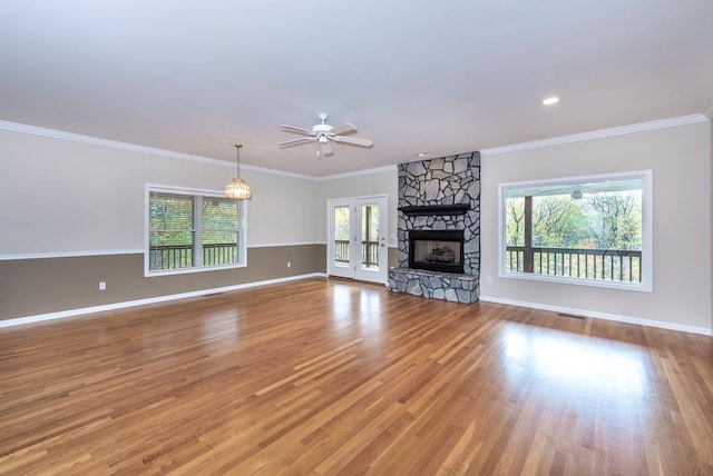 unfurnished living room with ornamental molding, plenty of natural light, wood-type flooring, and ceiling fan