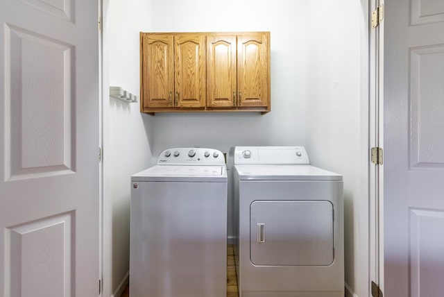 laundry area featuring separate washer and dryer and cabinets