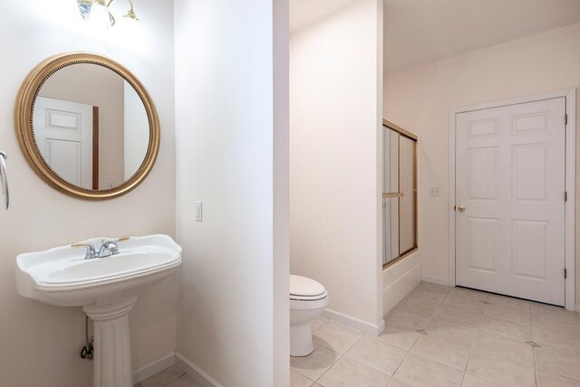 bathroom with bath / shower combo with glass door, tile patterned floors, and toilet