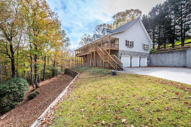 back of property featuring a garage, a wooden deck, and a lawn