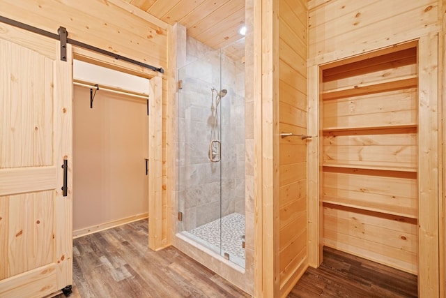 bathroom with hardwood / wood-style flooring, a shower with shower door, and wooden walls