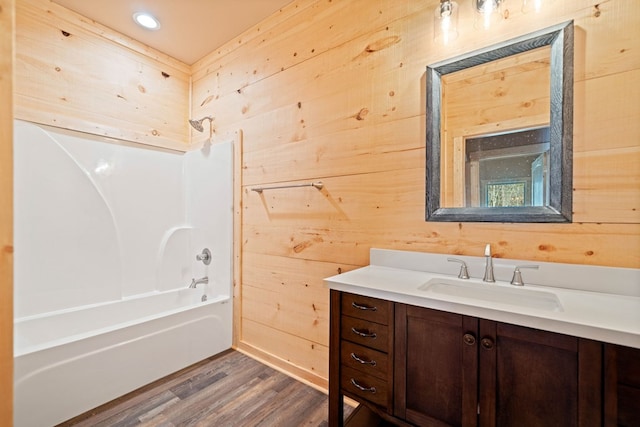 bathroom featuring wood walls, vanity, shower / bath combination, and hardwood / wood-style flooring