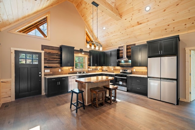 kitchen with wall chimney exhaust hood, hanging light fixtures, stainless steel appliances, high vaulted ceiling, and a breakfast bar