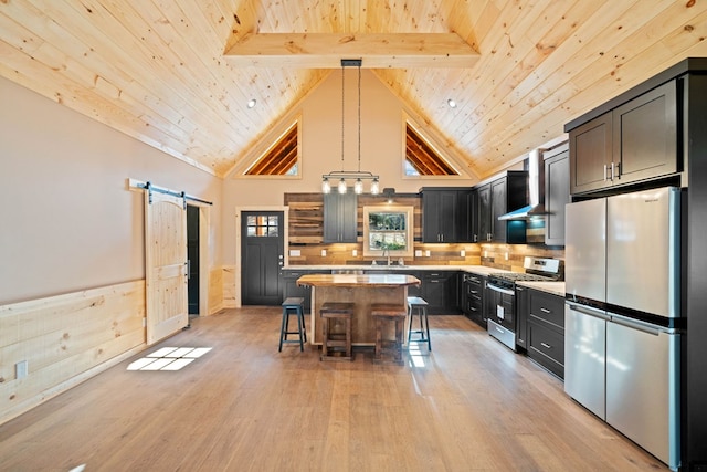 kitchen featuring appliances with stainless steel finishes, a kitchen breakfast bar, pendant lighting, a barn door, and a kitchen island