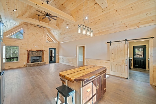 kitchen with hanging light fixtures, a barn door, beamed ceiling, high vaulted ceiling, and hardwood / wood-style flooring