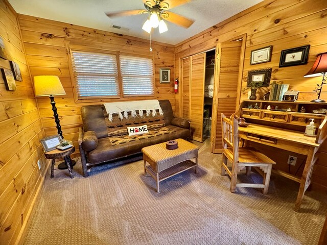 carpeted living room featuring ceiling fan and wooden walls