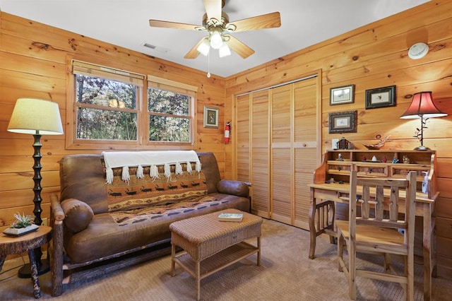 living room featuring carpet, wooden walls, and ceiling fan