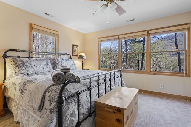 bedroom featuring ceiling fan, multiple windows, and light colored carpet