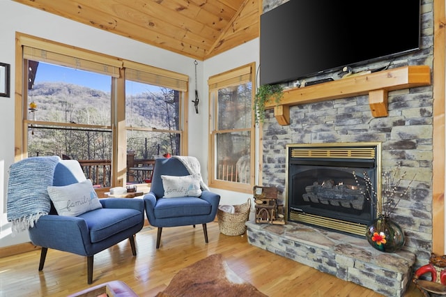 sitting room with light wood-type flooring, lofted ceiling, wooden ceiling, and a fireplace