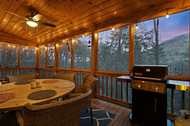 sunroom / solarium with vaulted ceiling, ceiling fan, and wooden ceiling