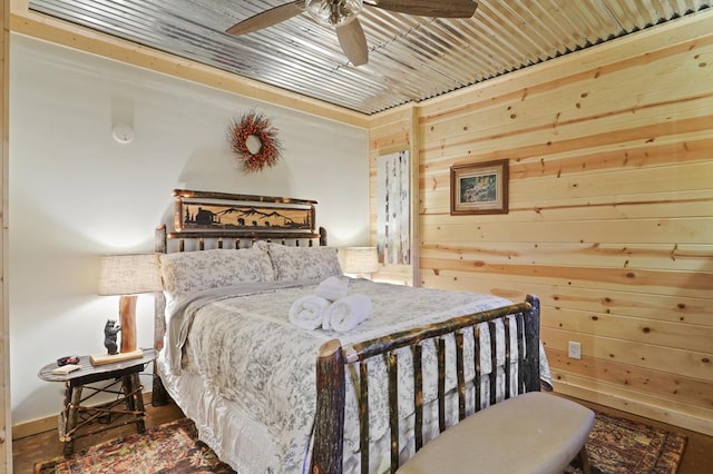 bedroom featuring dark hardwood / wood-style flooring, ceiling fan, and wooden walls