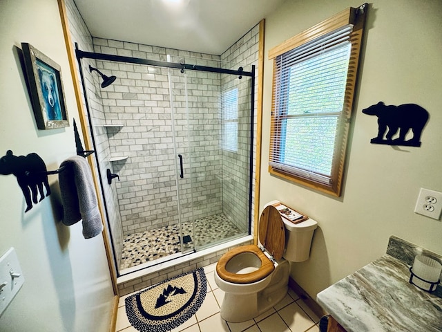 bathroom with a shower with shower door, vanity, toilet, and tile patterned floors