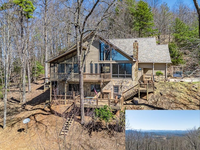 rear view of house featuring a sunroom, stone siding, a chimney, stairs, and a wooden deck