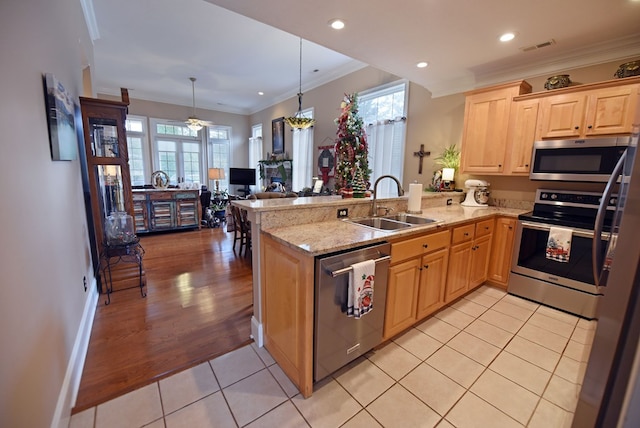 kitchen with decorative light fixtures, sink, light tile patterned floors, kitchen peninsula, and stainless steel appliances