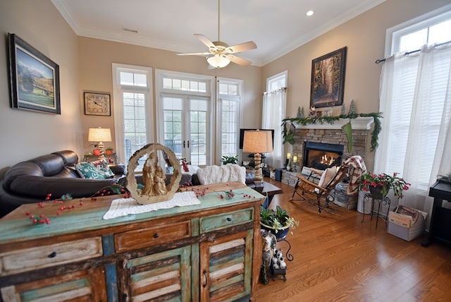 interior space with crown molding, wood-type flooring, a stone fireplace, and french doors