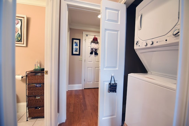 laundry area featuring hardwood / wood-style flooring, ornamental molding, and stacked washer and clothes dryer