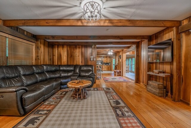 living room with beamed ceiling, wood walls, and light wood-type flooring