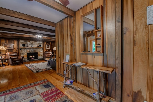 hall with beamed ceiling, light hardwood / wood-style flooring, and wood walls