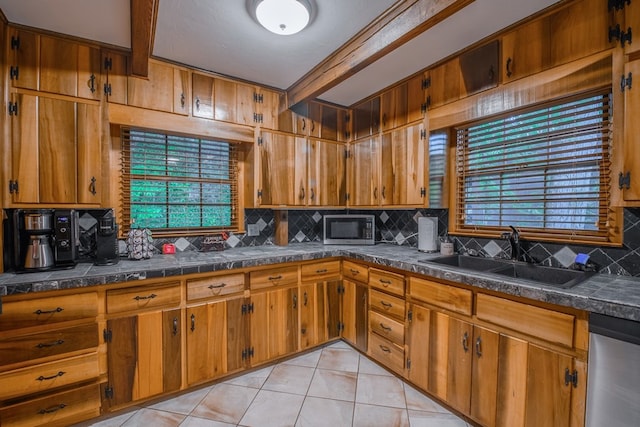 kitchen with backsplash, appliances with stainless steel finishes, sink, and light tile floors