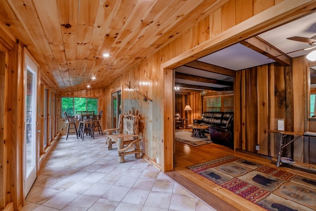 corridor with wood walls and light tile flooring