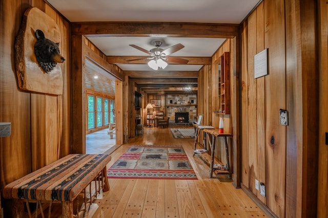 hallway with beamed ceiling, light hardwood / wood-style flooring, and wood walls