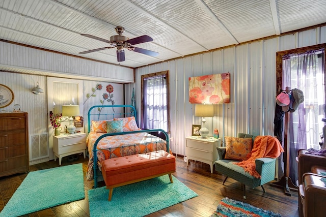 bedroom featuring wood walls, hardwood / wood-style floors, and ceiling fan