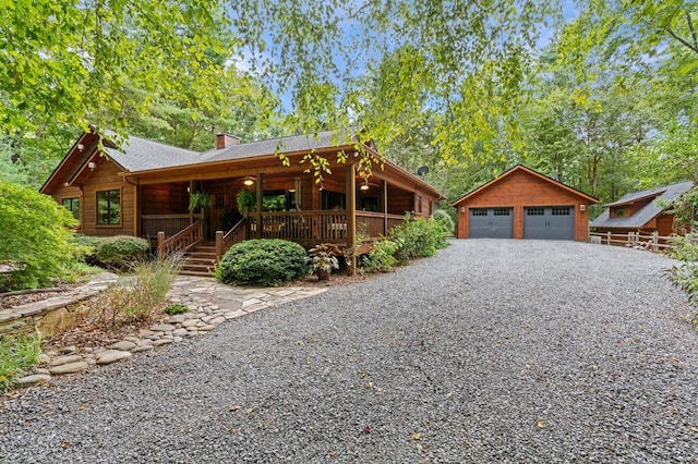 log home with covered porch, an outbuilding, and a garage