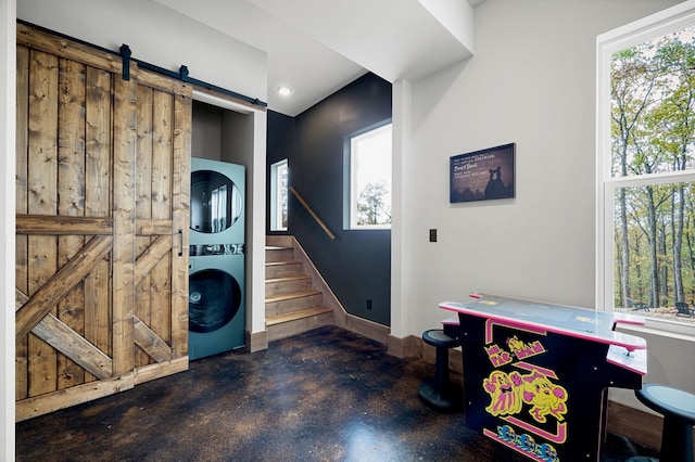 1250 Lost Forest Rd, Ellijay, GA 30536 - interior space featuring a barn door, stacked washer / dryer, baseboards, concrete floors, and stairs