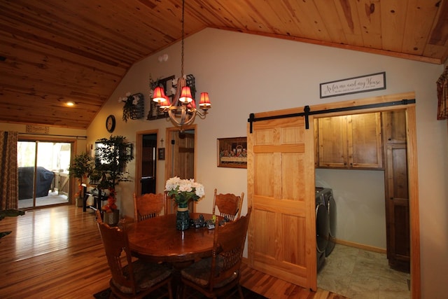 dining area featuring a notable chandelier, vaulted ceiling, a barn door, and washing machine and clothes dryer