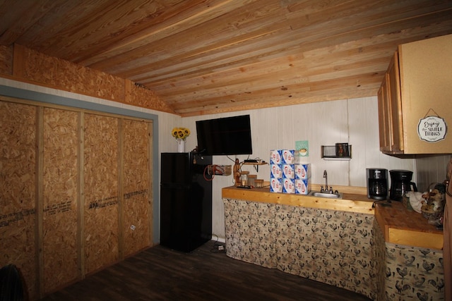 kitchen with black refrigerator, wooden ceiling, sink, and wooden walls