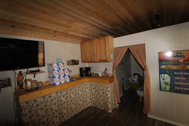 kitchen featuring dark hardwood / wood-style floors, wood walls, wooden ceiling, and sink