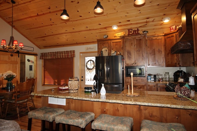 kitchen featuring kitchen peninsula, light stone countertops, stainless steel appliances, and premium range hood