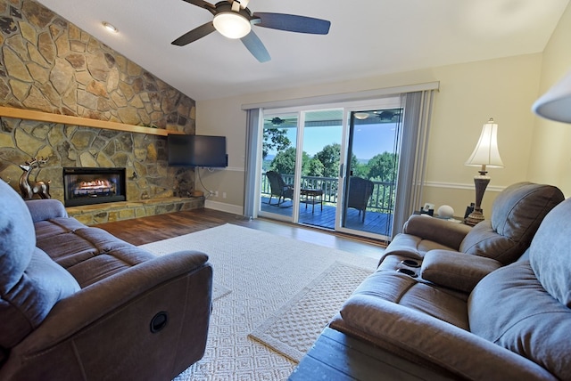 living room featuring a stone fireplace, ceiling fan, lofted ceiling, and hardwood / wood-style flooring