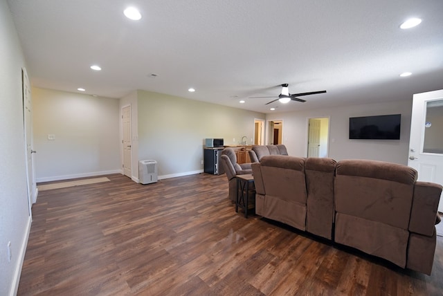 living room with ceiling fan, dark wood-type flooring, and a textured ceiling