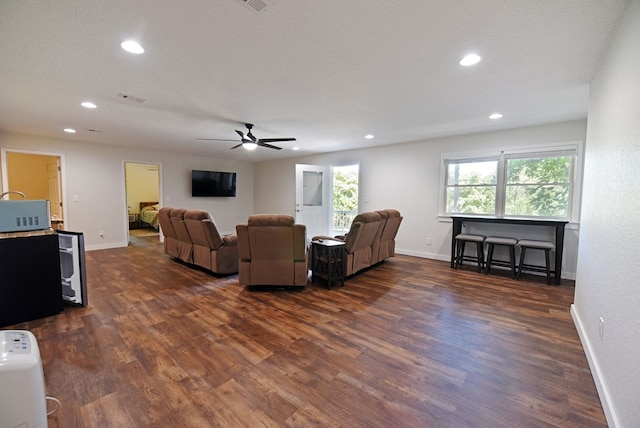 living room featuring ceiling fan, dark wood-type flooring, and a textured ceiling