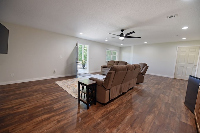 living room with ceiling fan, dark wood-type flooring, and a textured ceiling