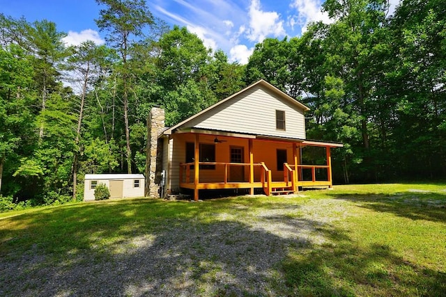 rear view of property featuring a wooden deck, a yard, and a shed