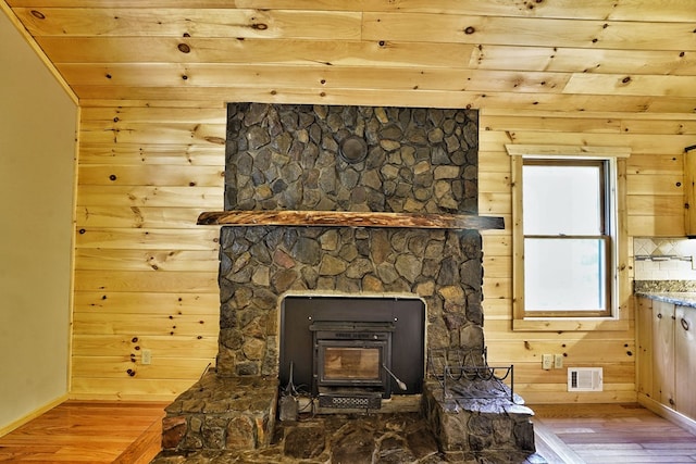 details with wood-type flooring, wooden walls, and a wood stove