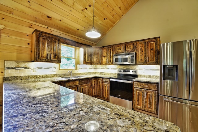 kitchen featuring sink, decorative light fixtures, dark stone countertops, appliances with stainless steel finishes, and decorative backsplash