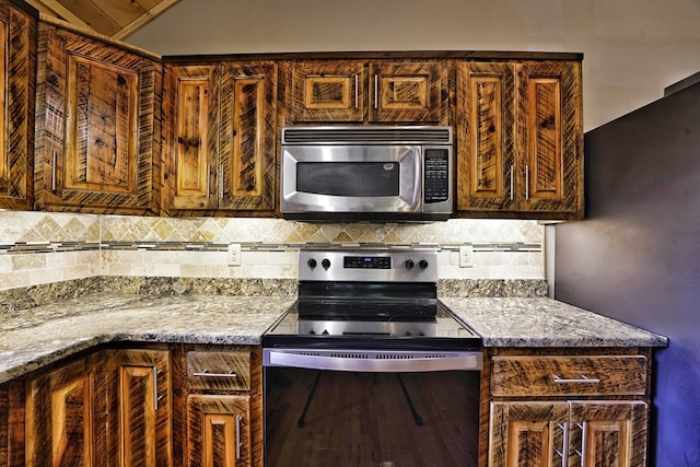 kitchen featuring light stone countertops, decorative backsplash, and stainless steel appliances