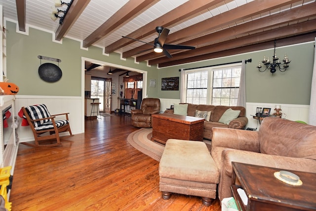 living room with hardwood / wood-style floors, beamed ceiling, and ceiling fan with notable chandelier