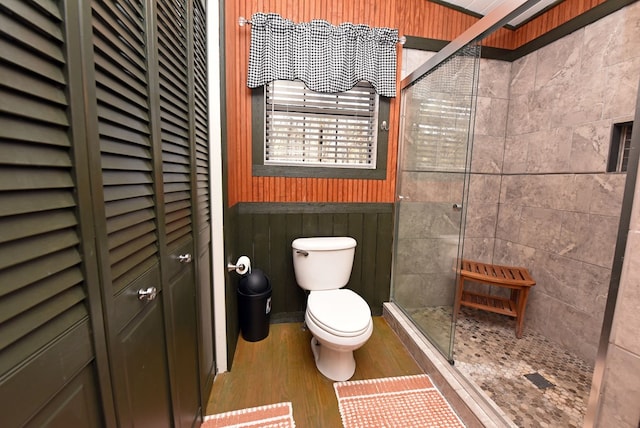 bathroom featuring hardwood / wood-style floors, toilet, and a shower with door