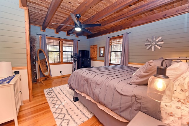 bedroom with wood walls, beamed ceiling, wooden ceiling, and light hardwood / wood-style floors